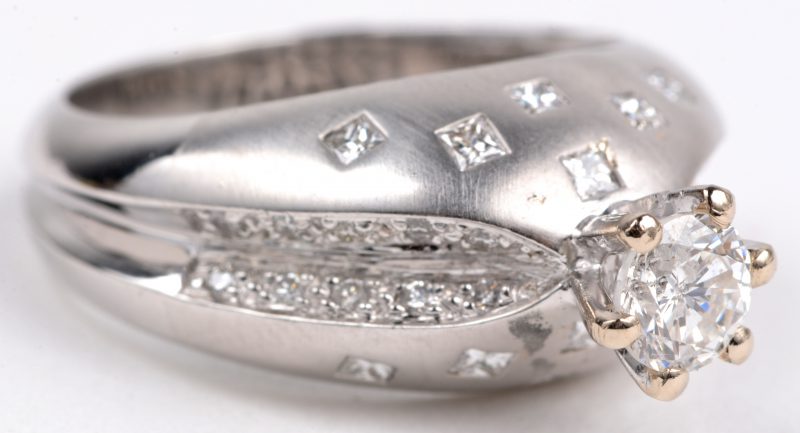 Een 18 karaats wit gouden ring bezet met briljanten en princesses met een gezamenlijk gewicht van ± 0,80 ct. en een centrale briljant van ± 0,50 ct.