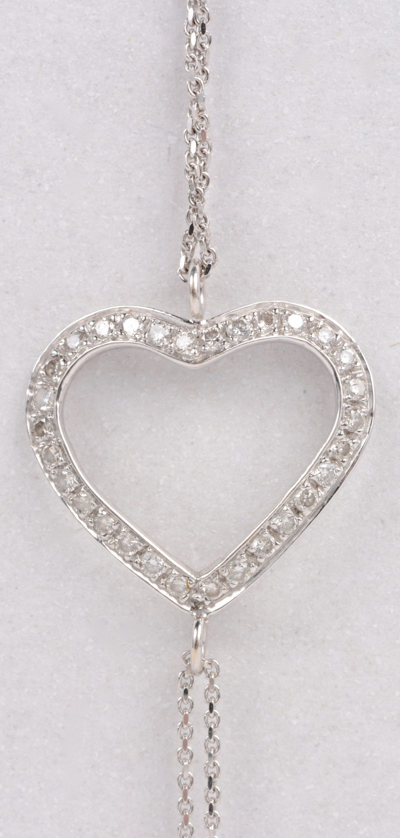 Een 18 karaats wit gouden armband met hartvormige hanger bezet met diamanten met een gezamenlijk gewicht van ± 0,18 ct.