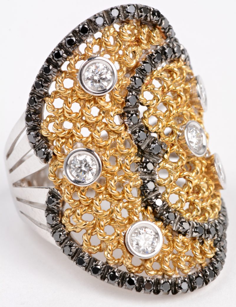 Een 18 karaats wit en geel gouden ring bezet met witte en zwarte diamanten met een gezamenlijk gewicht van ± 1,02 ct.