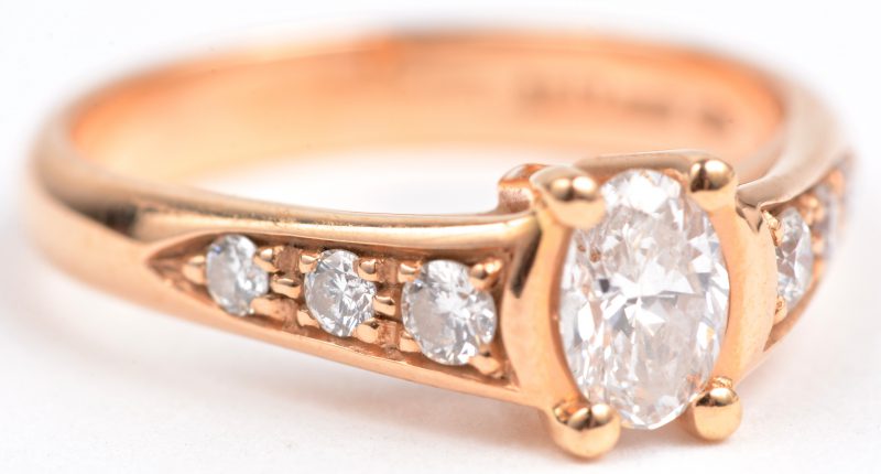 Een 18 karaats roze gouden ring bezet met een centrale diamant van ± 0,46 ct. en briljanten met een gezamenlijk gewicht van ± 0,26 ct.
