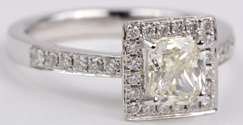 Een 18 karaats wit gouden ring bezet met een centrale diamant oude slijp van ± 1,05 ct. VS en diamanten met een gezamenlijk gewicht van ± 0,32 ct.