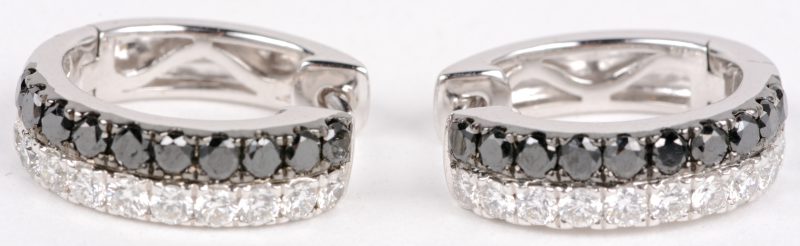 Een paar 18 karaats wit gouden oorbellen bezet met witte en zwarte diamanten met een gezamenlijk gewicht van ± 1,64 ct.