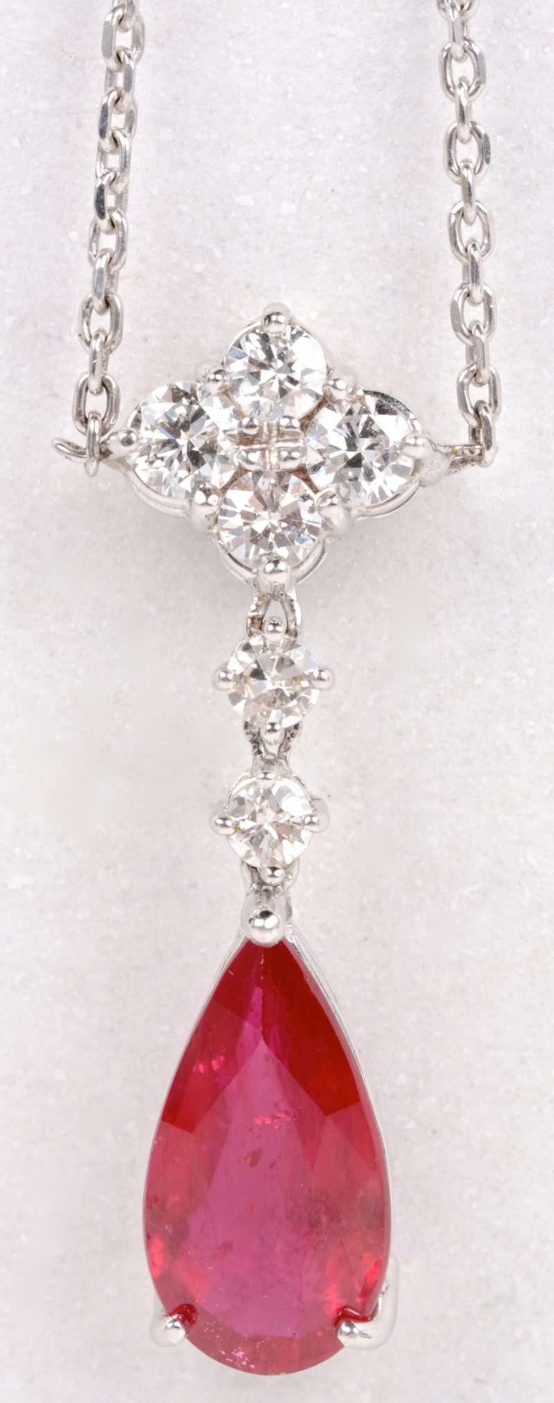 Een 18 karaats wit gouden ketting met hanger bezet met diamanten met een gezamenlijk gewicht van ± 0,64 ct. en een druppelvormige robijn van ± 3,80 ct.