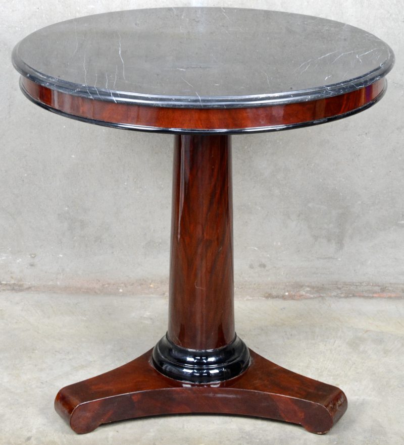 Een gefineerde ronde tafel in Empirestijl met een zwart marmeren blad.