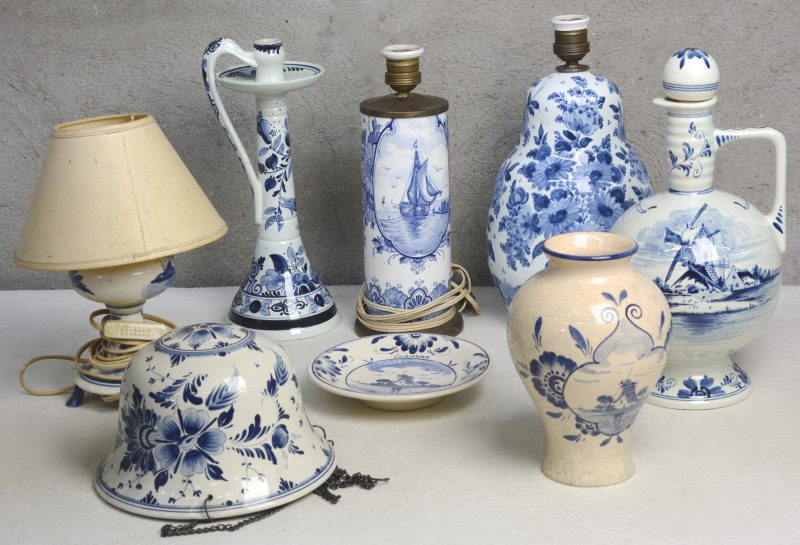 Een lot blauw en wit Hollands plateel, bestaande uit drie verschillende lampen, een hangjardinière, een fles, een hoge kandelaar, een vaas en een sierbord. Diverse merken.