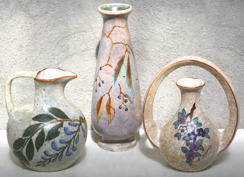 Twee siervazen van meerkleurig aardewerk, versierd met decors van A. Dubois. De langste met enkele kleine schilfers aan de voet. Jaren ‘10 & ‘20. Bijgevoegd een vaas van G. Dubois te Baudour.