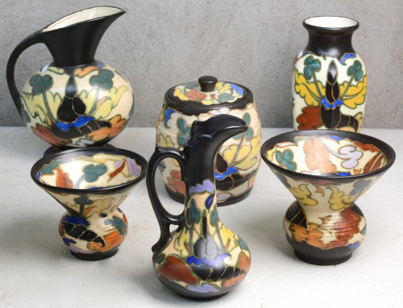 Een lot meerkleurig aardewerk in de stijl van Gouda, bestaande uit twee kwispedoors, een vaas, twee kannen en een tabakspot.