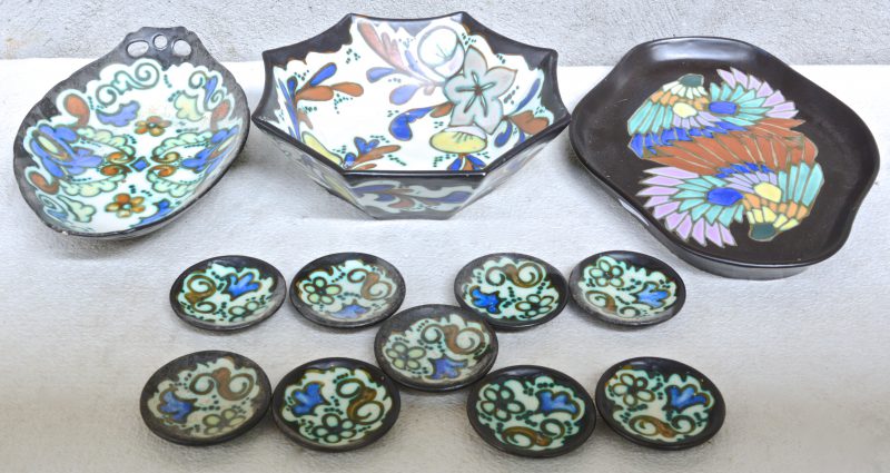 Een schaal met negen bordjes, een schotel en een achthoekige fruitschaal van meerkleurig aardewerk in de stijl van Gouda. Onderaan gemerkt.