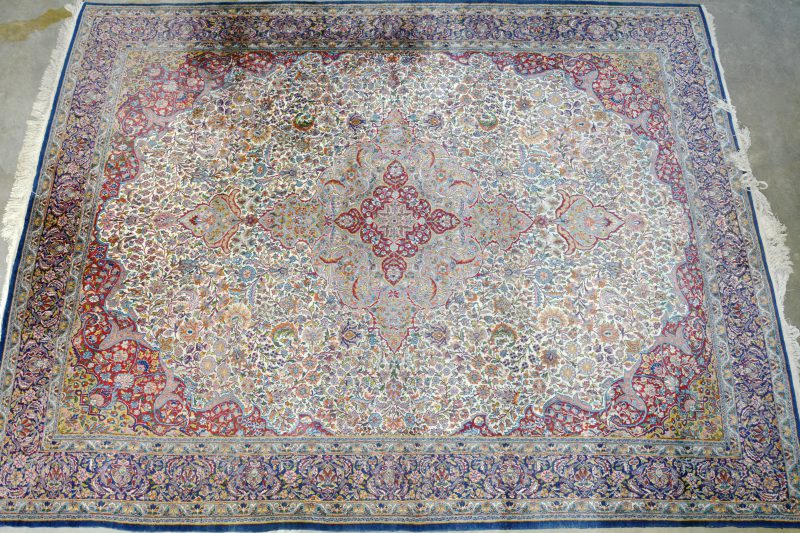 Handgeknoopt wollen tapijt. Centraal medaillon omgeven door bloemenmotieven. Brede heratiboord. Perzisch werk. Lichte randslijtage.
