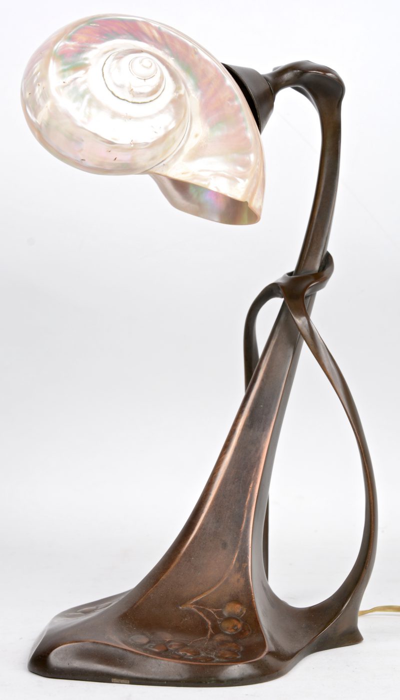 Een art nouveau bureaulamp van verkoperd tin met een nautilusschelp als kap.