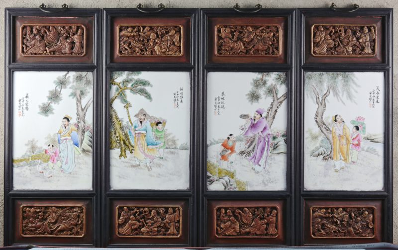 Een reeks van vier porseleinen plaquettes met meerkleurige decors van personages in landschappen. In gesculpteerde houten lijsten. Chinees werk.