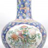 Een overwegend blauwe Chinese lange hals vaas van porselein met personages en bloemen. Onderaan gemerkt.