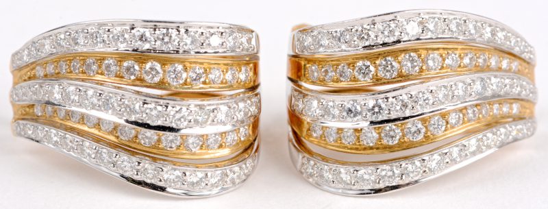 Een paar 18 karaats wit en geel gouden oorbellen bezet met diamanten met een gezamenlijk gewicht ± 1,84 ct.