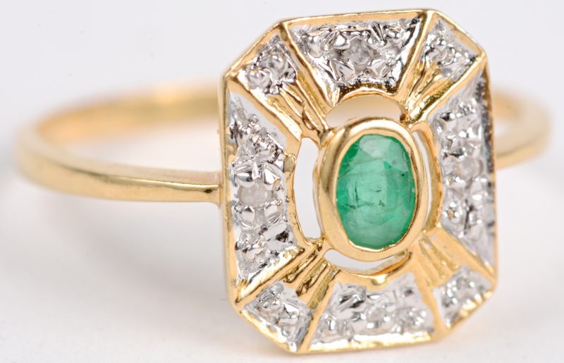 Een 18 karaats wit en geel gouden ring bezet met een centrale smaragd van ± 0,15 ct. en kleine diamantjes.