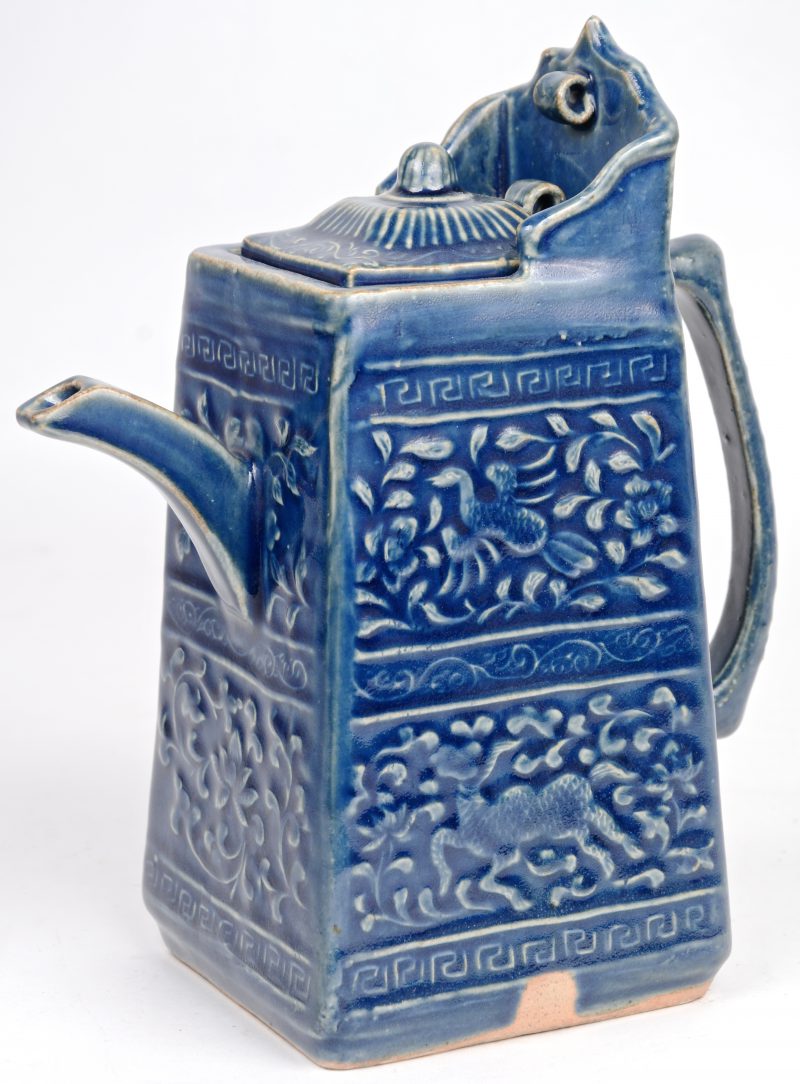 Een vierhoekige theepot van blauwgeglazuurd Chinees aardewerk.