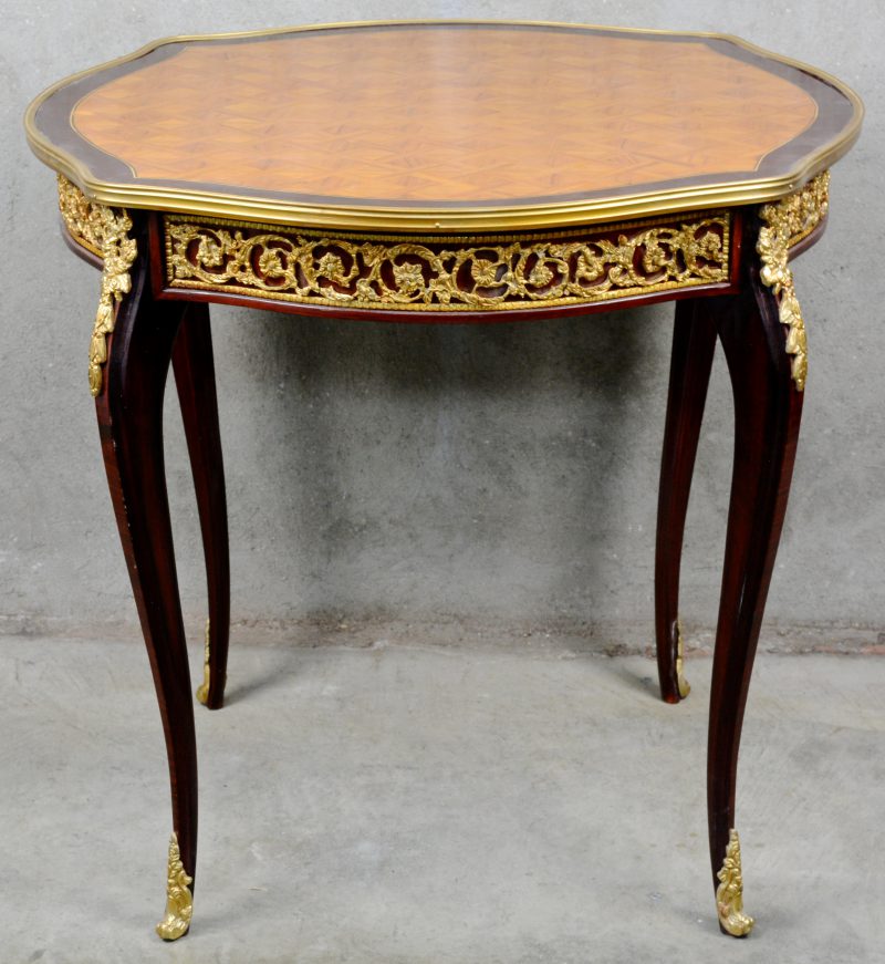 Een gefineerd houten tafel in Lodewijk XV-stijl, versierd met verguld bronsbeslag en met parketwerk.