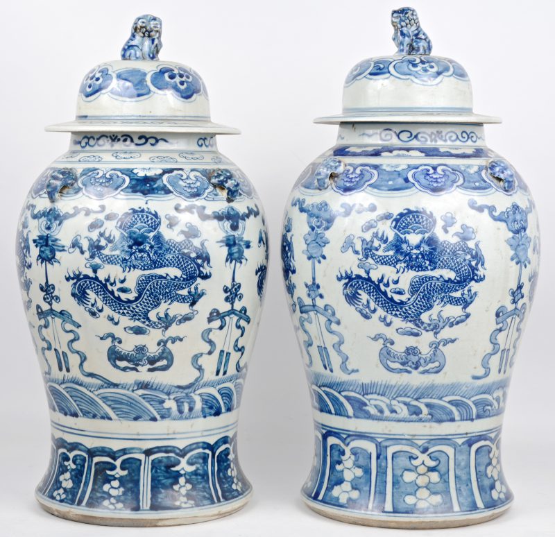 Een paar dekselvazen van Chinees porselein met blauw op wit drakendecor en de deksels getooid met tempelleeuwen.