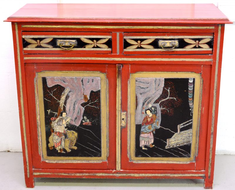 Een roodgelakt buffetkastje met twee laden en twee deuren, versierd met Chinese decors.
