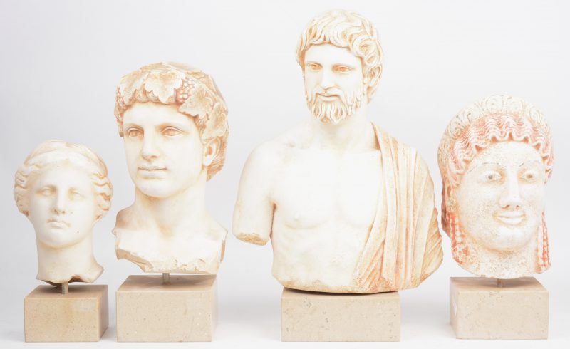 Vier plaasteren replica’s van romeinse bustes op beige marmeren sokkels.