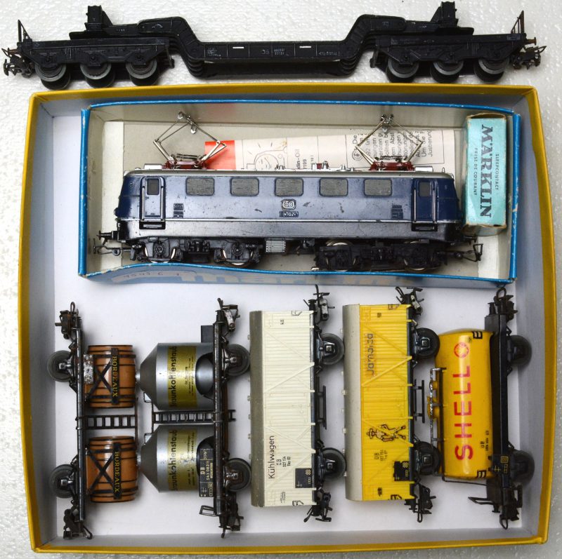 Een elektrische locomotief van de Duitse spoorwegen op schaal HO. Bijgevoegd zes verschillende goederenwagons, bestaande uit een tankwagen van Shell, een dieplader, een silowagen, een wagon met wijnvaten, een koelwagen en een bananenwagen.