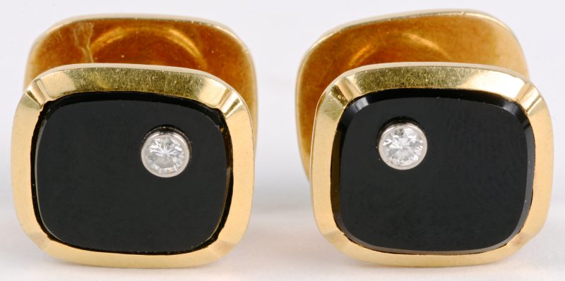 Een paar 18 karaats geel gouden manchetknopen bezet met diamanten met een gezamenlijk gewicht van ± 0,20 ct. en onyx.