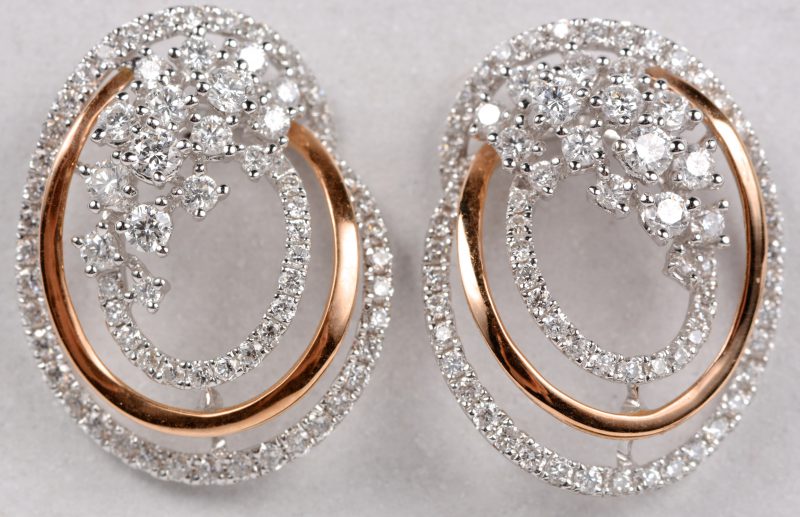 Een paar 18 karaats wit en roze gouden oorbellen bezet met diamanten met een gezamenlijk gewicht ± 1,77 ct.
