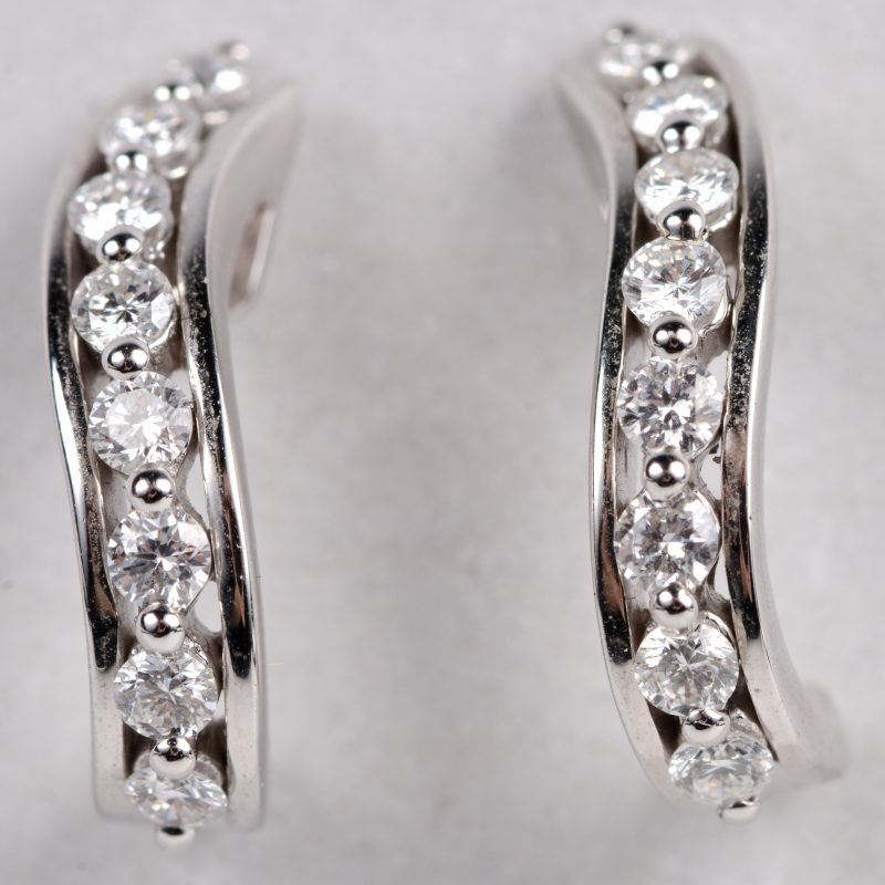 Een paar 18 karaats wit gouden oorbellen bezet met diamanten met een gezamenlijk gewicht ± 0,58 ct.