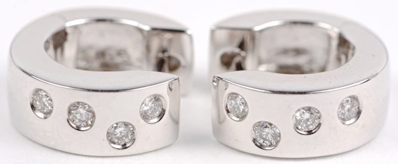Een paar 18 karaats wit gouden oorbellen bezet met diamanten met een gezamenlijk gewicht ± 0,16 ct.