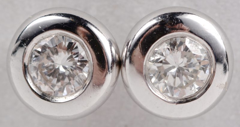 Een paar 18 karaats wit gouden oorbellen bezet met diamanten met een gezamenlijk gewicht ± 0,24 ct.