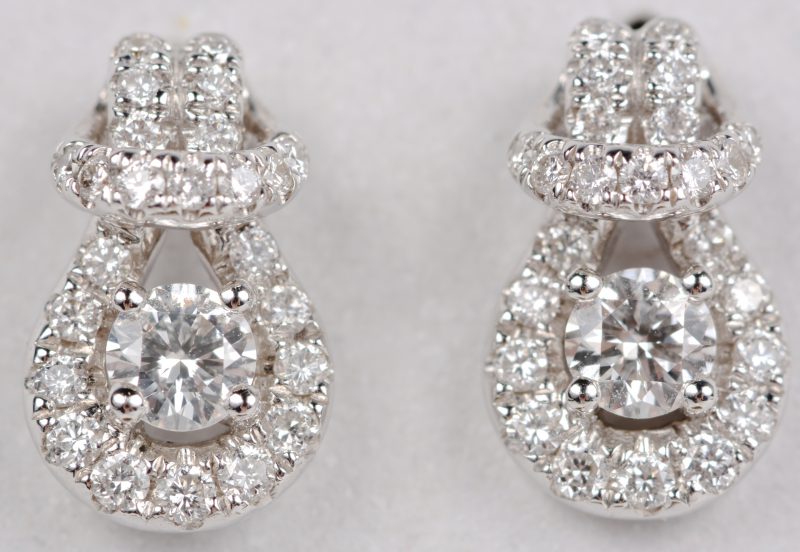 Een paar 18 karaats wit gouden oorbellen bezet met diamanten met een gezamenlijk gewicht ± 0,56 ct.