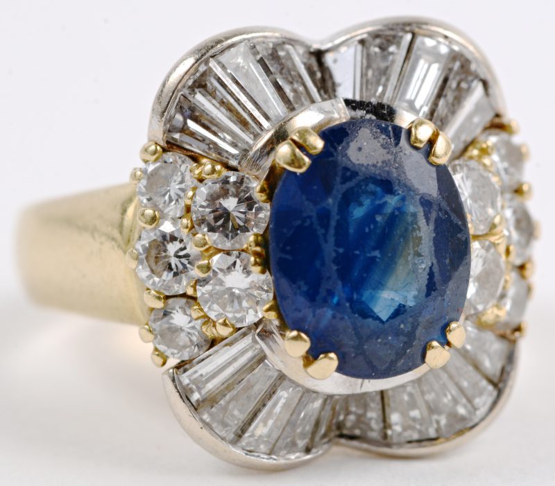 Een 18 karaats geel gouden ring bezet met diamanten en baguettes met een gezamenlijk gewicht van ± 1,50 ct. en een centrala saffier van ± 2 ct.