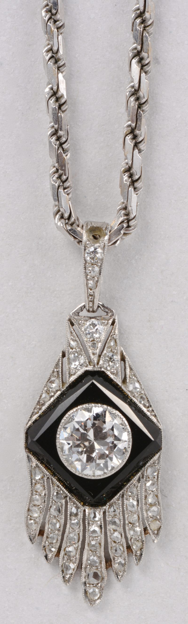 Een 18 karaats wit gouden ketting met hanger bezet met een centrale diamant van ± 1 ct. en briljanten met een gezamenlijk gewicht van ± 0,30 ct. en onyx.