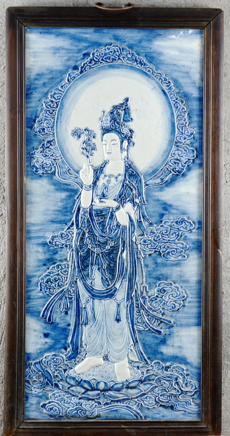 Een plaquette van blauw-wit Chinees porselein met een Boeddhistische voorstelling in reliëf. In houten lijst.