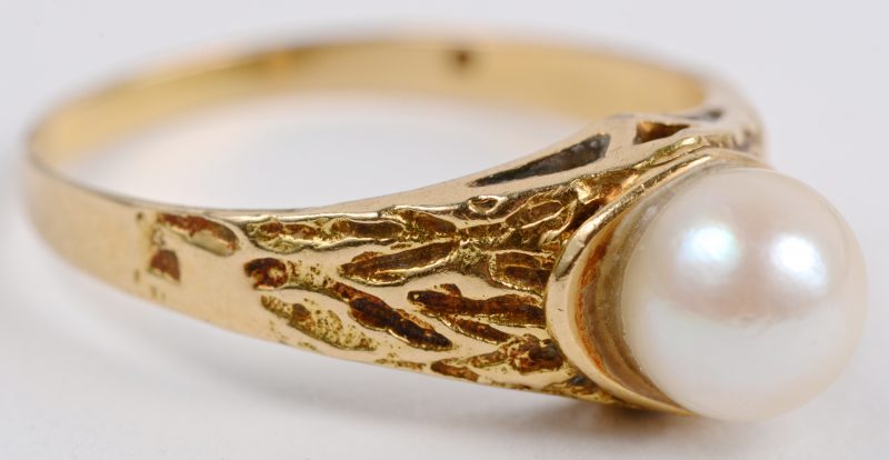 Een 18 karaats geel gouden graveerde ring bezet met een parel.
