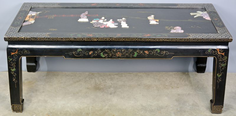 Een rechthoekige Chinese salontafel van zwartgelakt hout met decor van pietra dura.