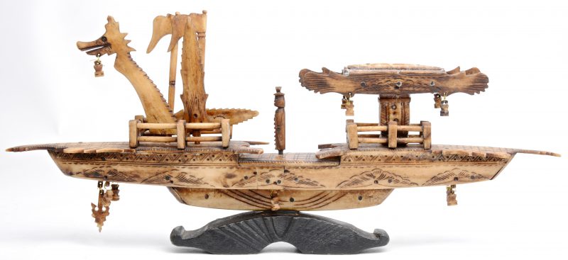 Een Chinese boot van been. Op houten voetstukje.