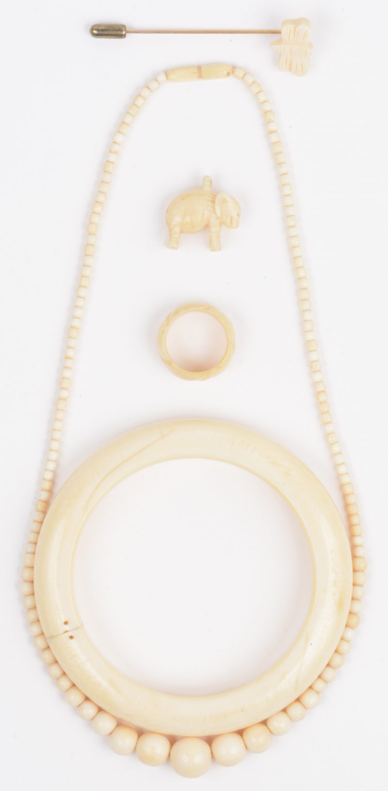 Een lot ivoren juwelen waaronder een speld, een halssnoer, een armband, twee hangertjes en een ring.