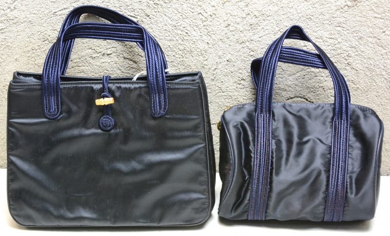 Twee zwarte handtasjes met blauwe draagriempjes.