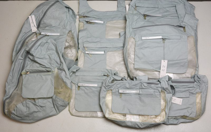Een lot van zes schoudertassen, twee rugzakjes en een heuptasje in grijs polyester en doorschijnend plastic.