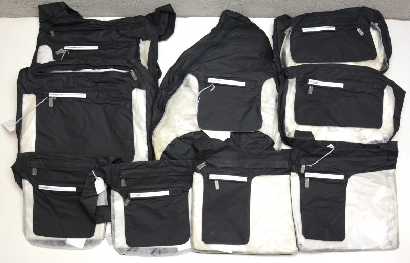 Twee grote en twee kleine schoudertassen, twee handtassen, twee heuptasjes en een rugzakje in zwart polyester en doorschijnend plastic.