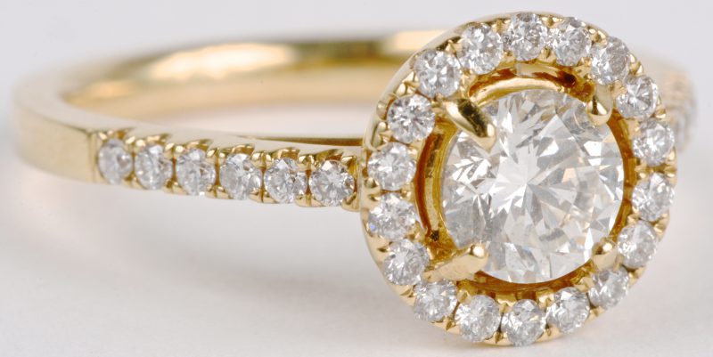 Een 18 karaats geel gouden ring bezet met een centrale diamant van ± 0,73 ct. en diamanten met een gezamenlijk gewicht ± 0,36 ct.