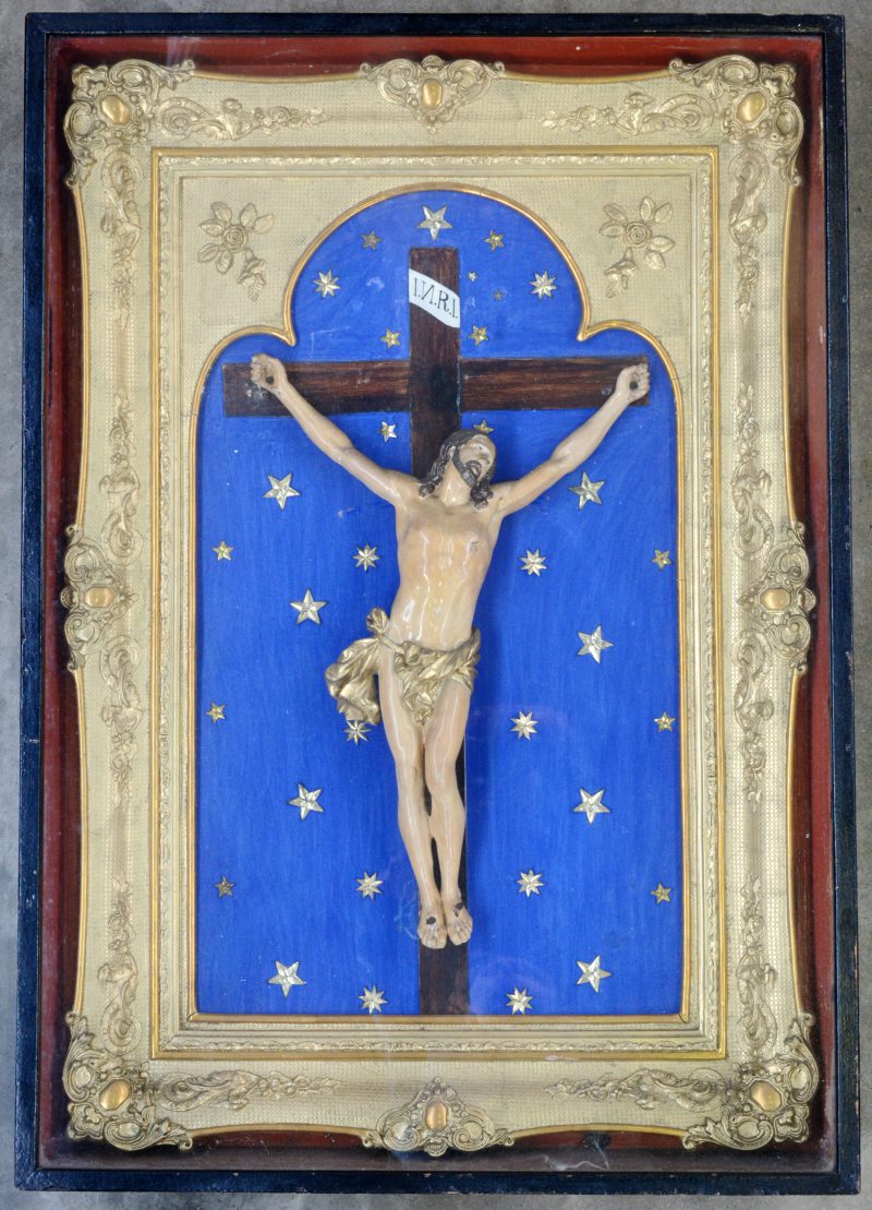 Een kruisbeeld in vergulde lijst met een meerkleurig en verguld gipsen corpus. Achter glas. XIXe eeuw.