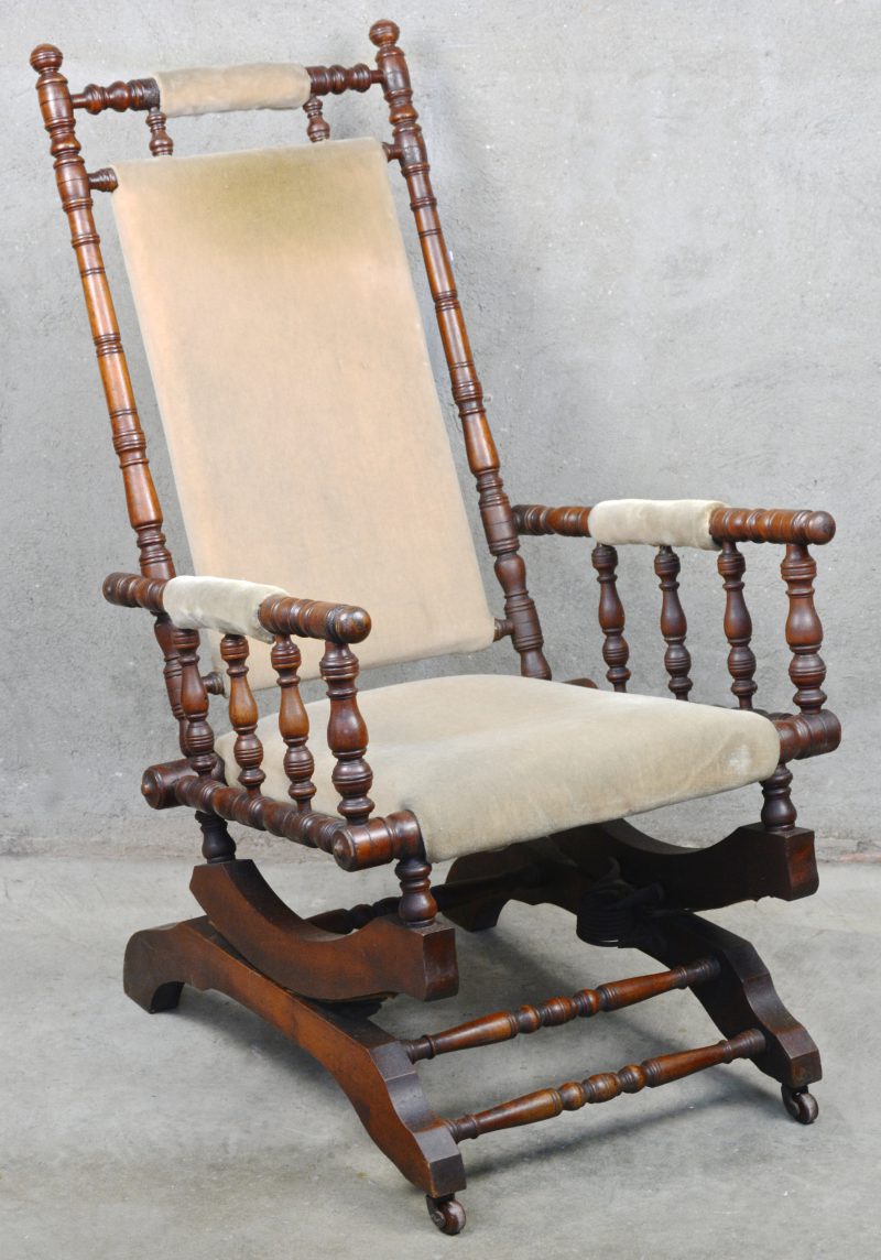 Een antieke schommelstoel van gedraaid mahoniehout en met fluwelen bekleding.
