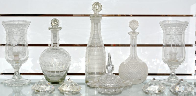 Een lot kleurloos kristal en glaswerk, bestaande uit vier in briljant geslepen kristallen presse-papiers, drie glazen karaffen, een paar windlichten en een stolp.