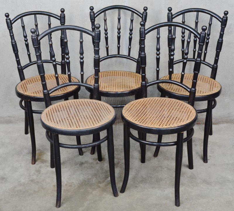 Een reeks van vijf stoelen van zwartgelakt hout met gecanneerde zit.