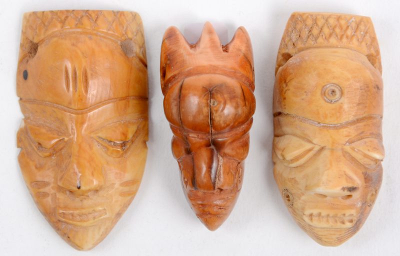 Drie kleine amuletten van gebeeldhouwd ivoor in de vorm van miniatuurmaskers. Congo, begin XXste eeuw.
