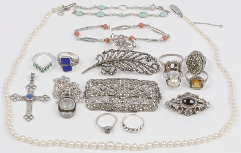 Een lot zilveren juwelen van 925 en 835 ‰ waaronder een parelhalssnoer een ketting met hanger een kruis, ringen, twee armbanden en twee broches, sommige bezet met halfedelstenen.