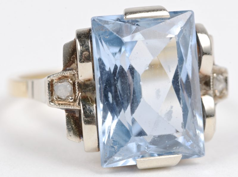 Een 18 karaats geel gouden ring bezet met twee kleine diamanten een lichtblauwe kleursteen van ± 4 ct.
