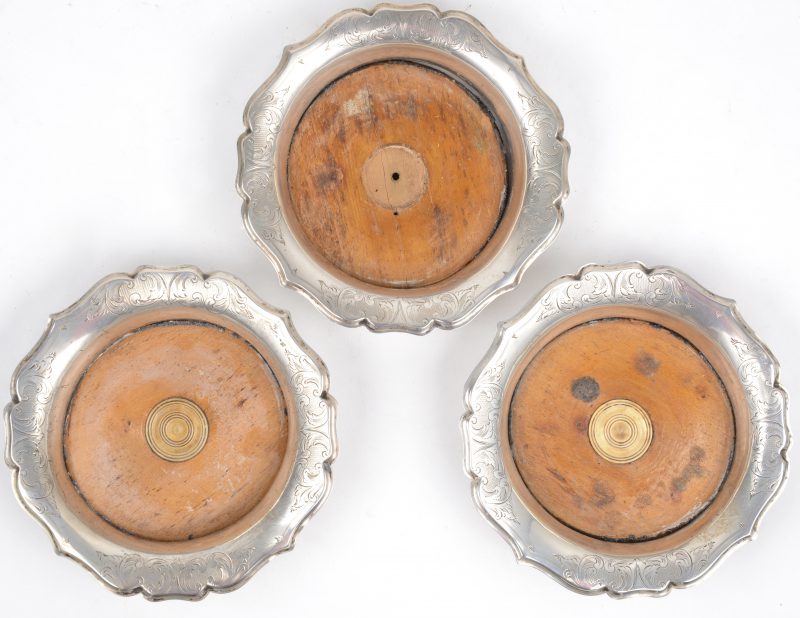 Drie zilveren flessenonderzetters (wine coasters) met gedraaide houten bodems (slijtage). Hollandse keuren, tweede gehalte, 1855. Meesterkeur J.M.