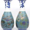 Een paar Japanse vazen met een cloisonné decor van vlinders, vogels en planten op wit porselein. Basis, hals en rand versierd in blauw en wit. Onderaan gemerkt. Tiijdperk Meiji. Een schilfer aan een onderrand.